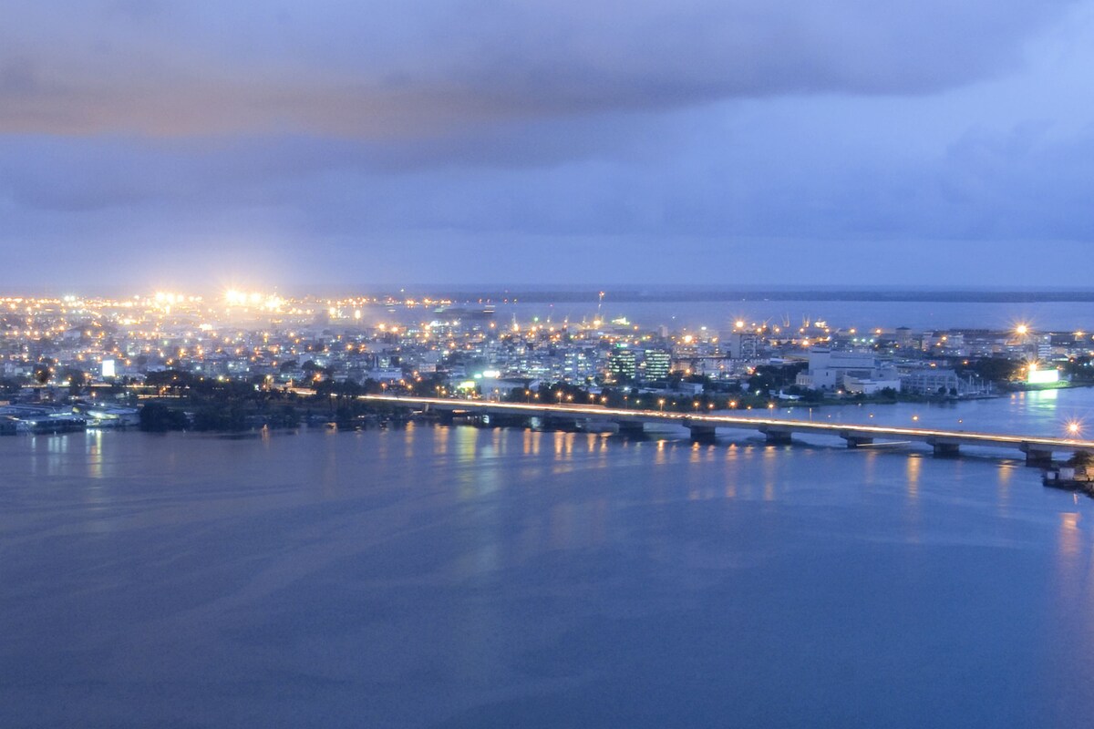 Une vue d’une ville côtière au crépuscule, avec un pont imposant et une vue sur le front de mer.