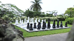 Un grand échiquier installé en plein air, avec les pièces d’échecs disposées dans un parc.
