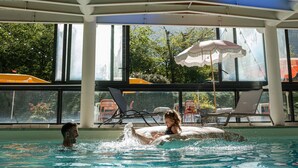 An indoor swimming pool with clear glass walls, lounge chairs, and umbrellas. -  Big Sky Hotel & Spa (Chamonix-Mont-Blanc)