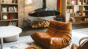 A cozy living room with a leather sofa, a round table, and a fireplace. -  Big Sky Hotel & Spa (Chamonix-Mont-Blanc)