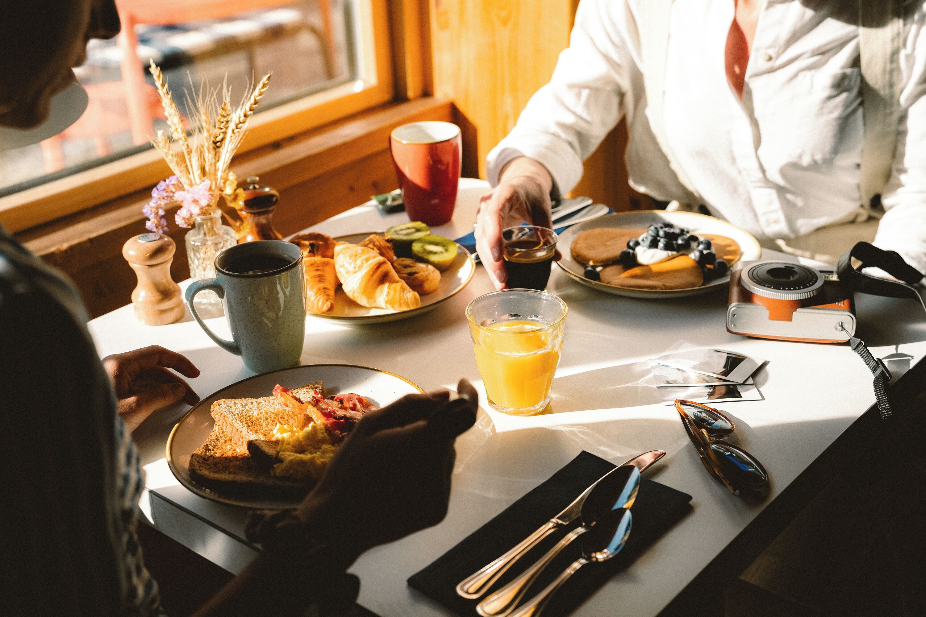 Una mesa de desayuno con platos de comida, una taza de café y una cámara.