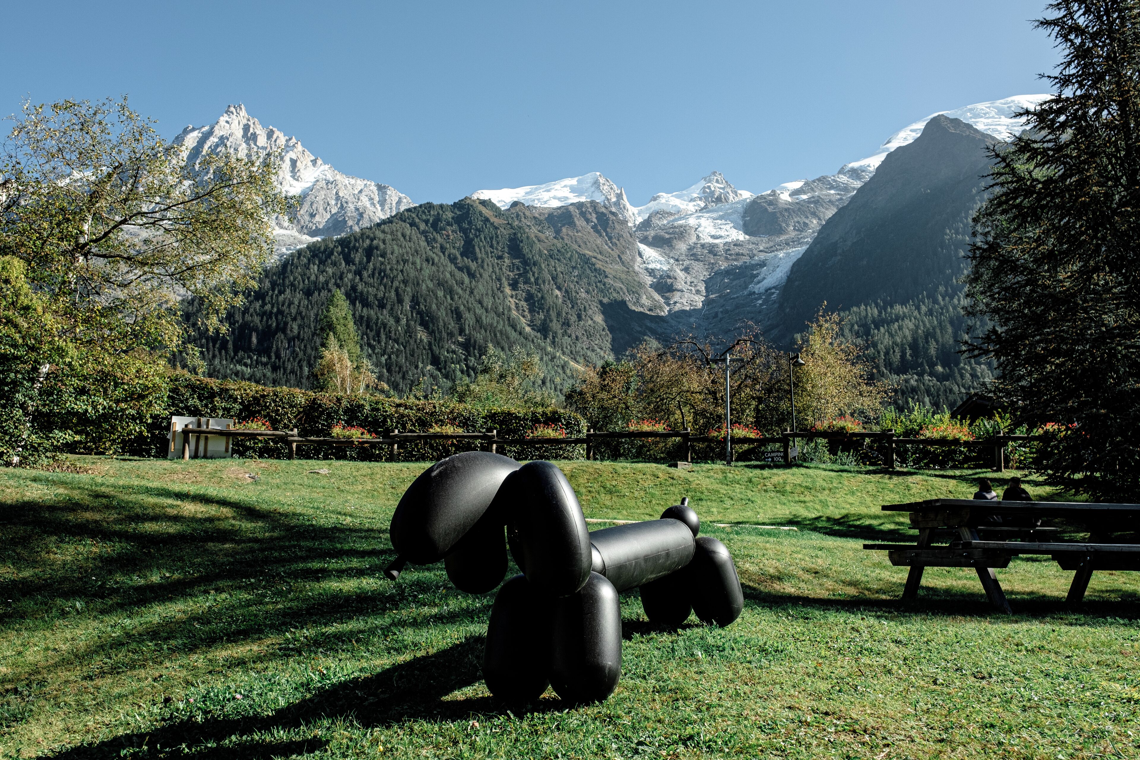 Un parc agrémenté d’une sculpture de chien, de bancs et d’une table de pique-nique.