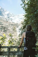 Una persona de pie junto a una valla de madera con vistas a un paisaje montañoso.