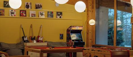 Una habitación acogedora con mesa de billar, mesa de futbolín y guitarras en la pared.
