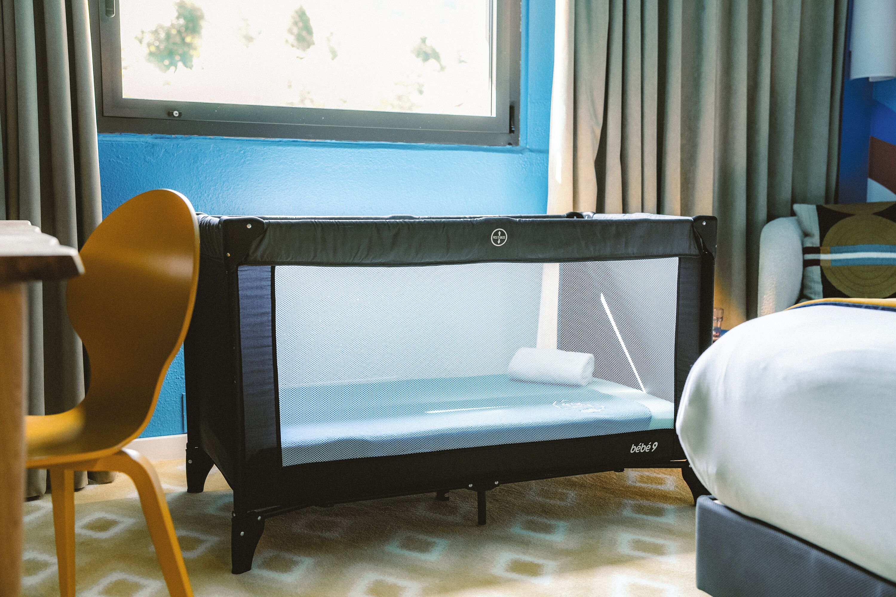 Une pièce avec un lit, un petit trampoline et une chaise.