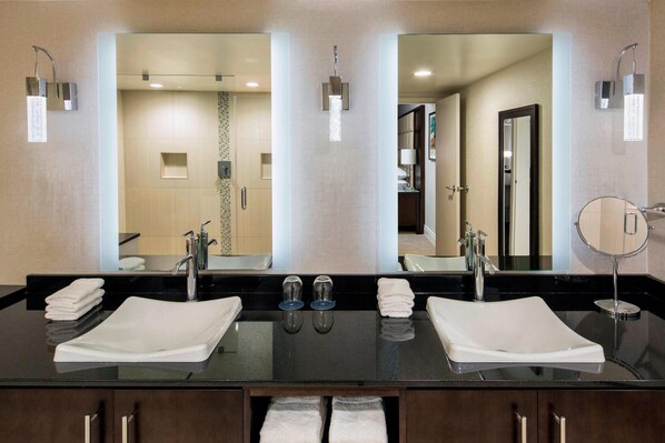 Un baño moderno con dos lavamanos, un espejo grande y un perchero para toallas.