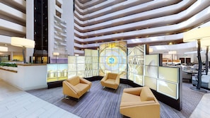 A modern lobby with a high ceiling, tiered seating, and a large digital display wall.