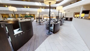 Un moderno vestíbulo de hotel con una zona de estar central, varias mesas y un letrero que dice 'PARK PLACE'.
