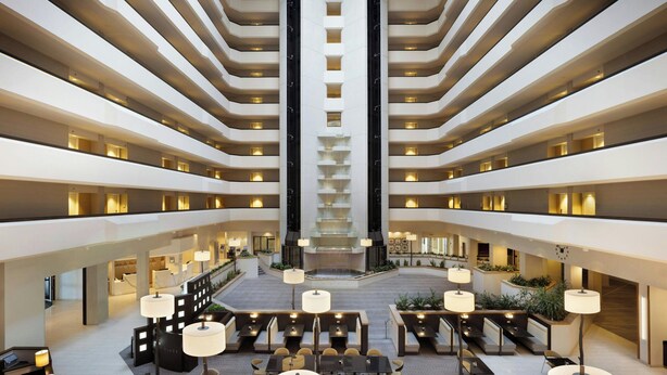 Vestíbulo de hotel de varios niveles con un atrio central, zonas de estar y una escalera.