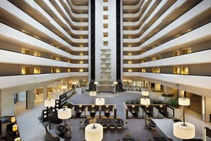 A multi-level hotel lobby with a central atrium, seating areas, and a staircase.