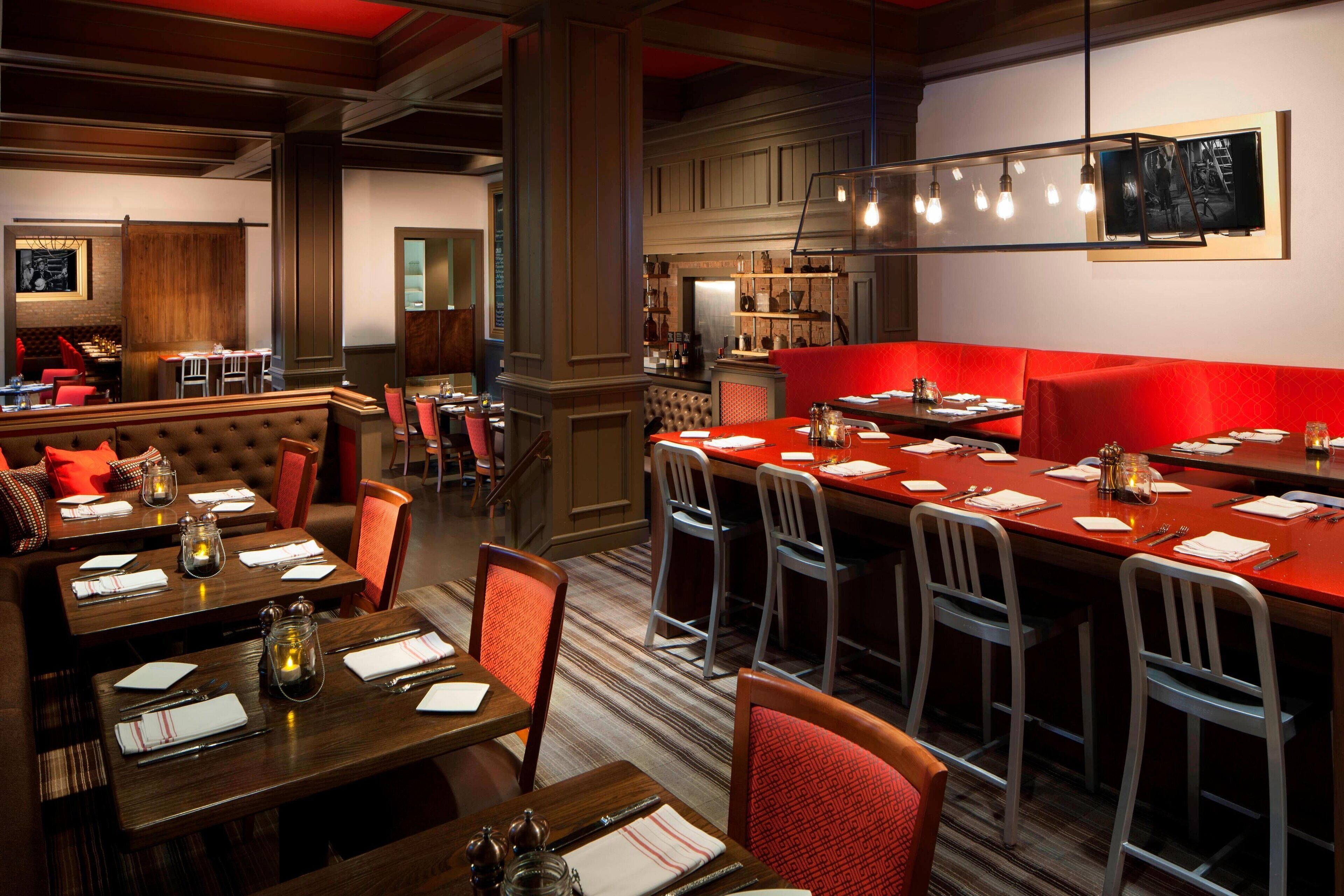 A restaurant with multiple dining areas, including booths and tables, and a bar area with a red seating section.