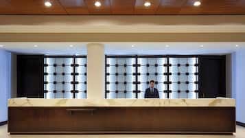 A reception desk with a marble top, wooden base, and a grid-patterned wall behind it.