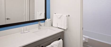 A bathroom with a white sink, a mirror, a towel rack, and a bathtub.
