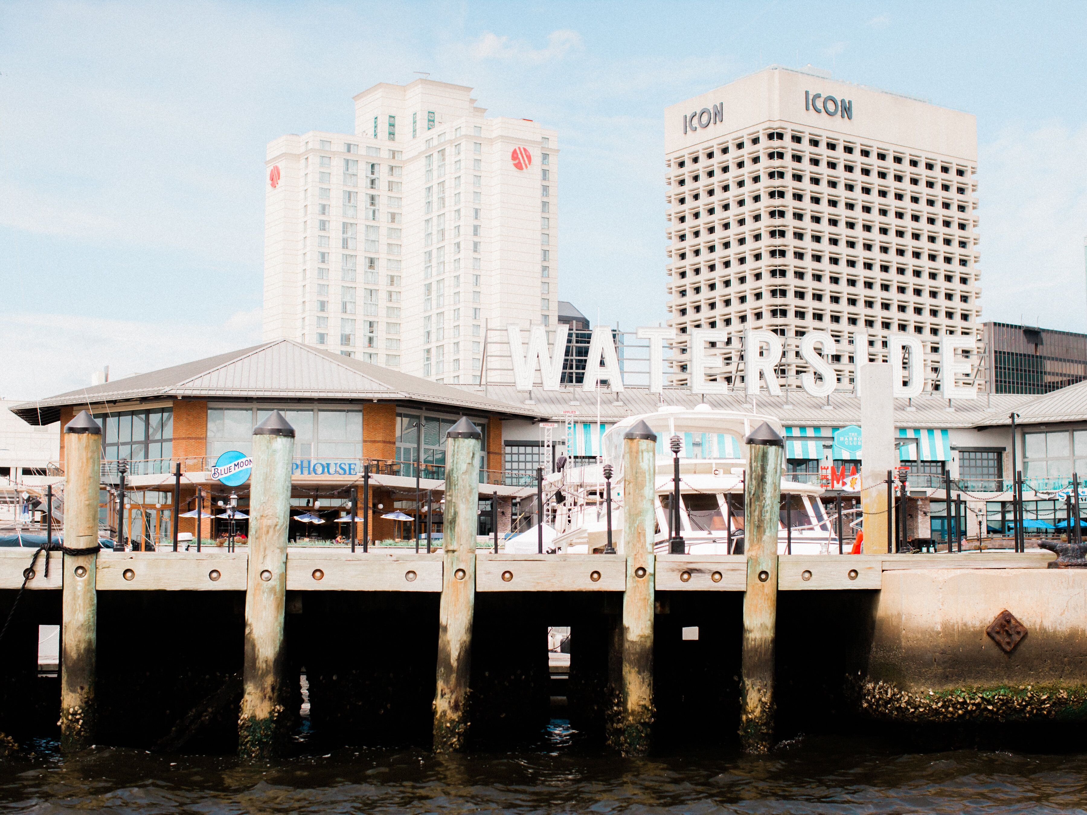 A waterfront building with multiple floors, a prominent 'ICON' sign, and a dock with boats.