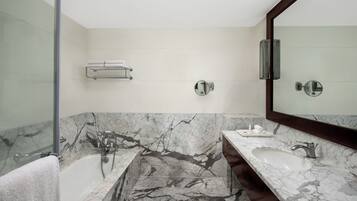 A modern bathroom with a marble vanity, a large mirror, and a glass shower enclosure.