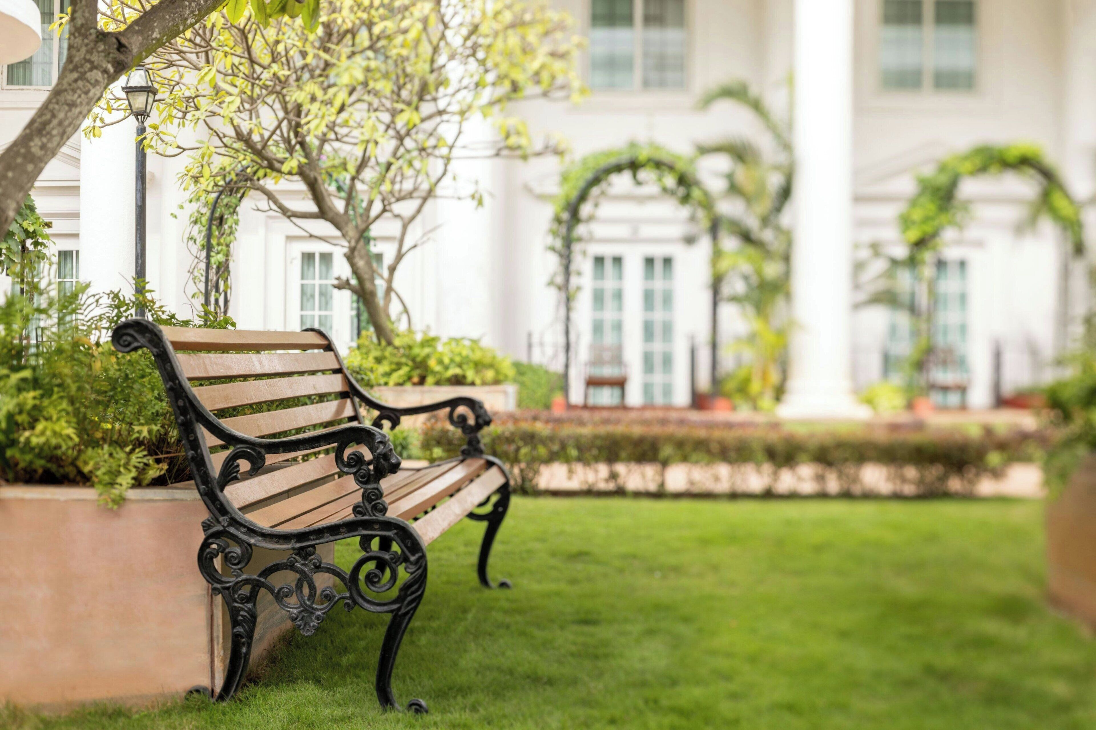 A bench in a garden area with a building in the background.