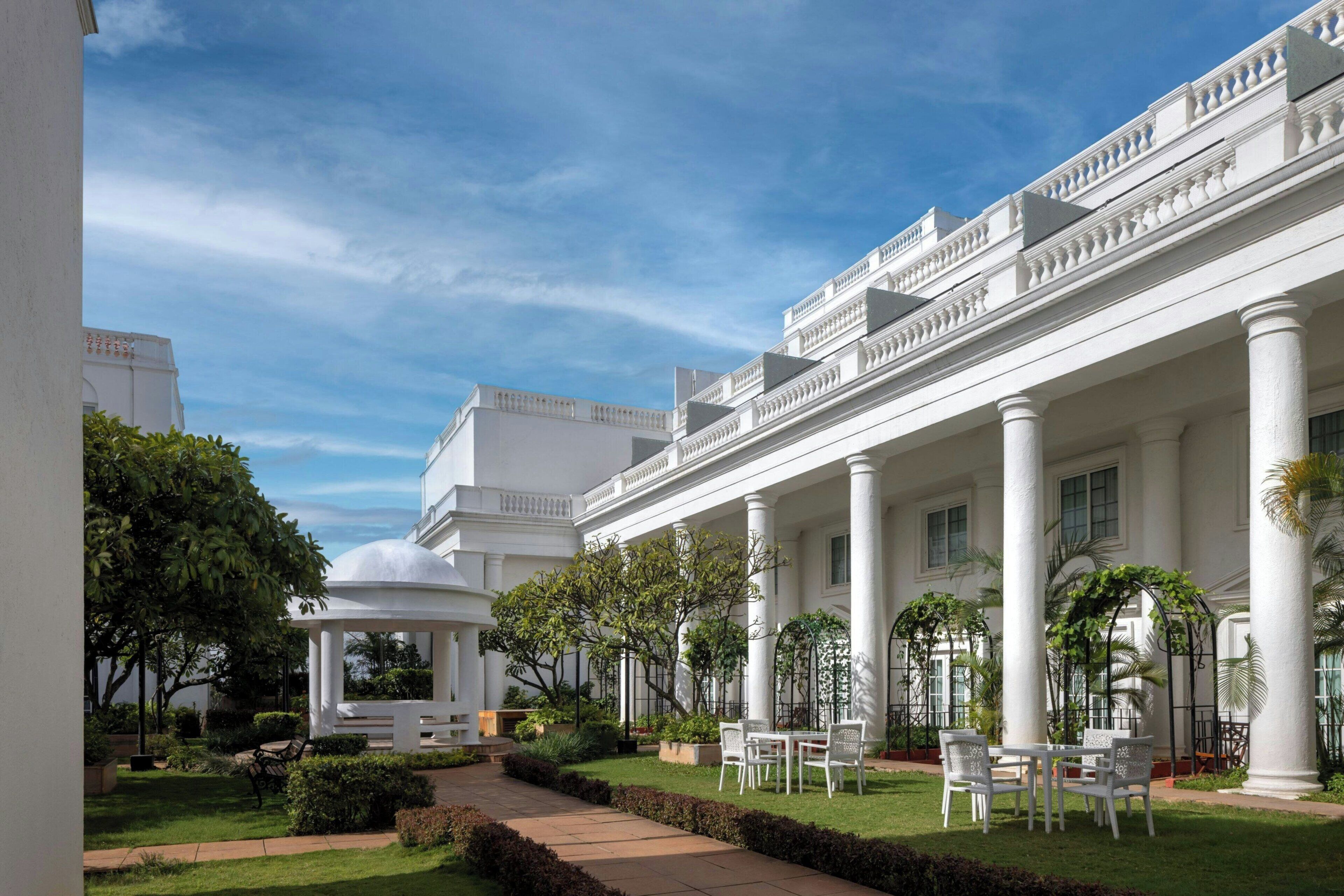 A white building with columns and a covered patio area with chairs and tables.