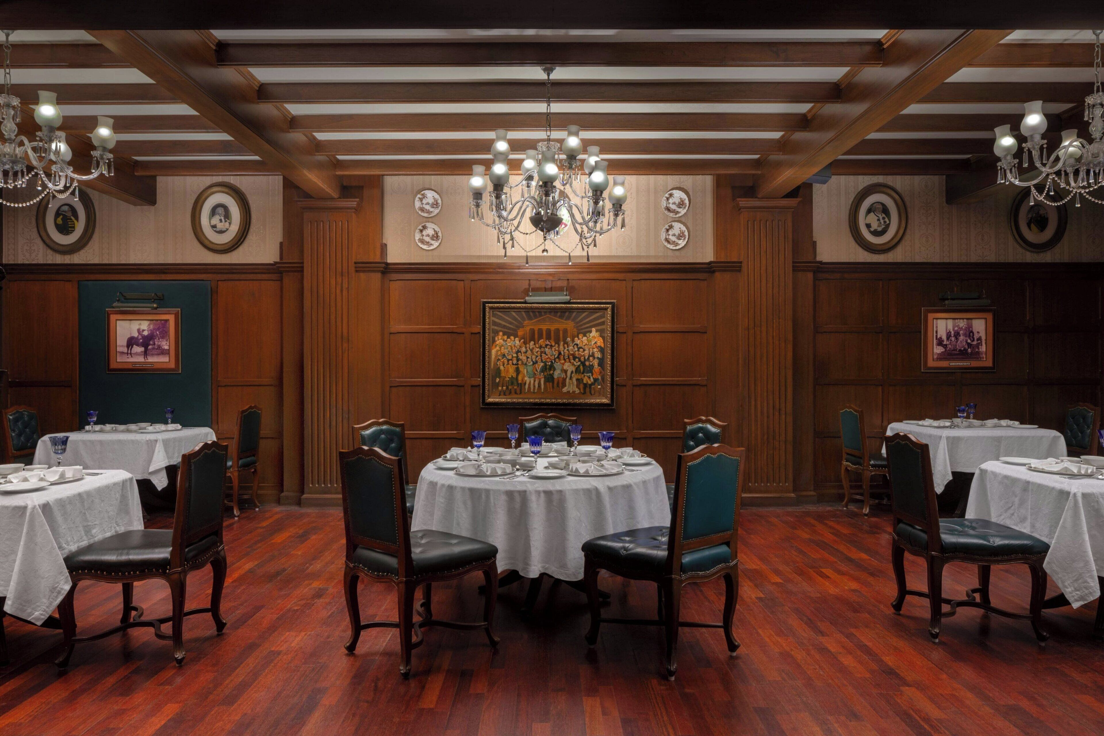 Une salle à manger avec des tables rondes, des chaises et des lustres.