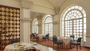 A dining area with round tables, chairs, and a glass partition.