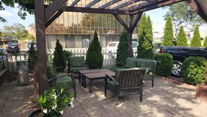 An outdoor patio area with a pergola, seating, and potted plants. - Birch Hill Grand Rapids (Grand Rapids)