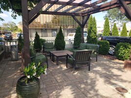 An outdoor patio area with a pergola, seating, and potted plants.