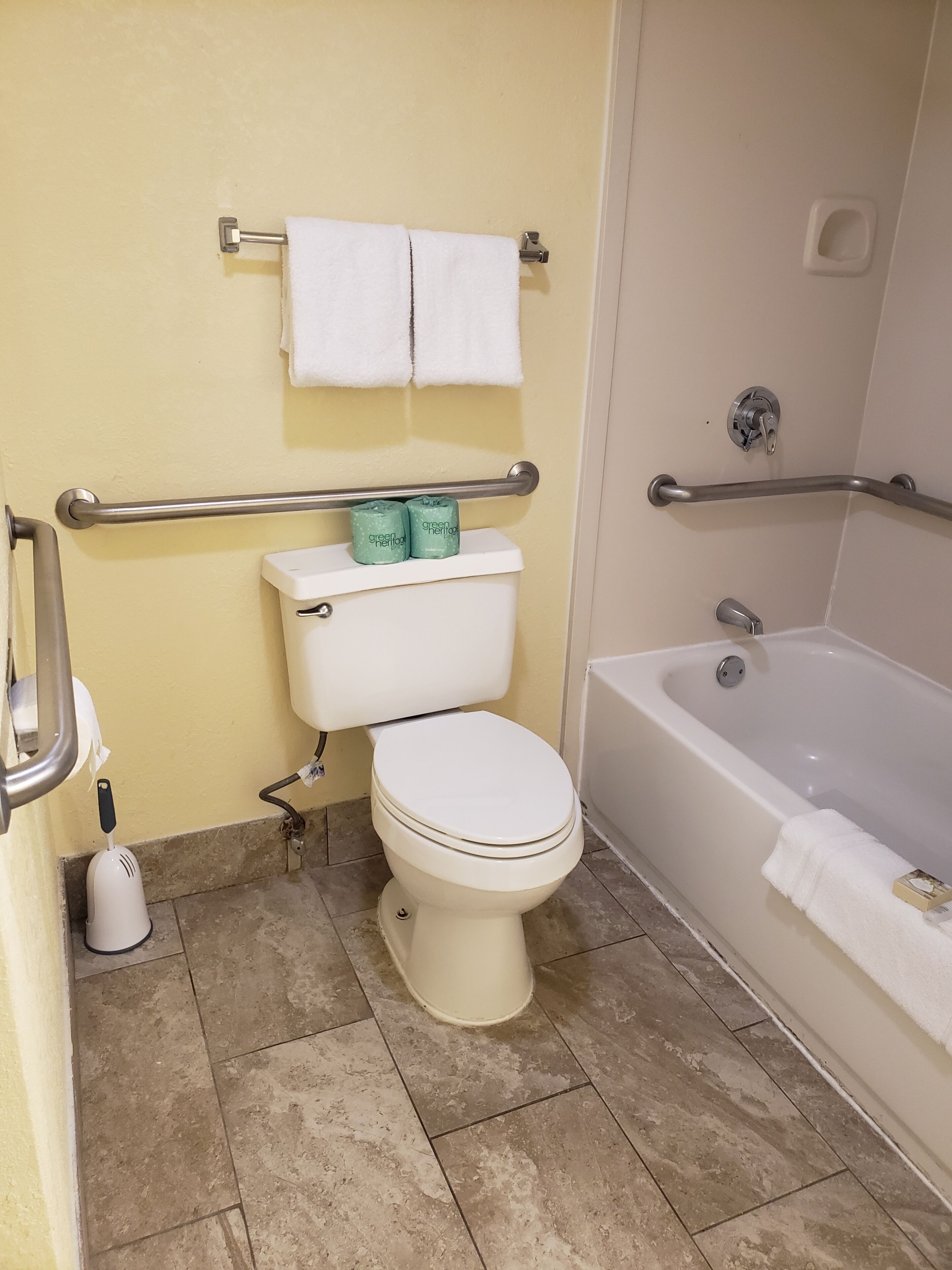 A bathroom with a toilet, a bathtub, and a shower. There are two white towels hanging on a rack above the toilet.