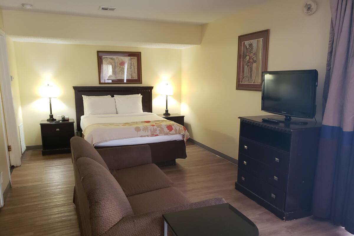Une chambre d’hôtel comprenant un lit, deux lampes de chevet, une télévision, un canapé et une petite table.