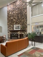 A living room with a stone wall, fireplace, orange sofa, and a ceiling fan.