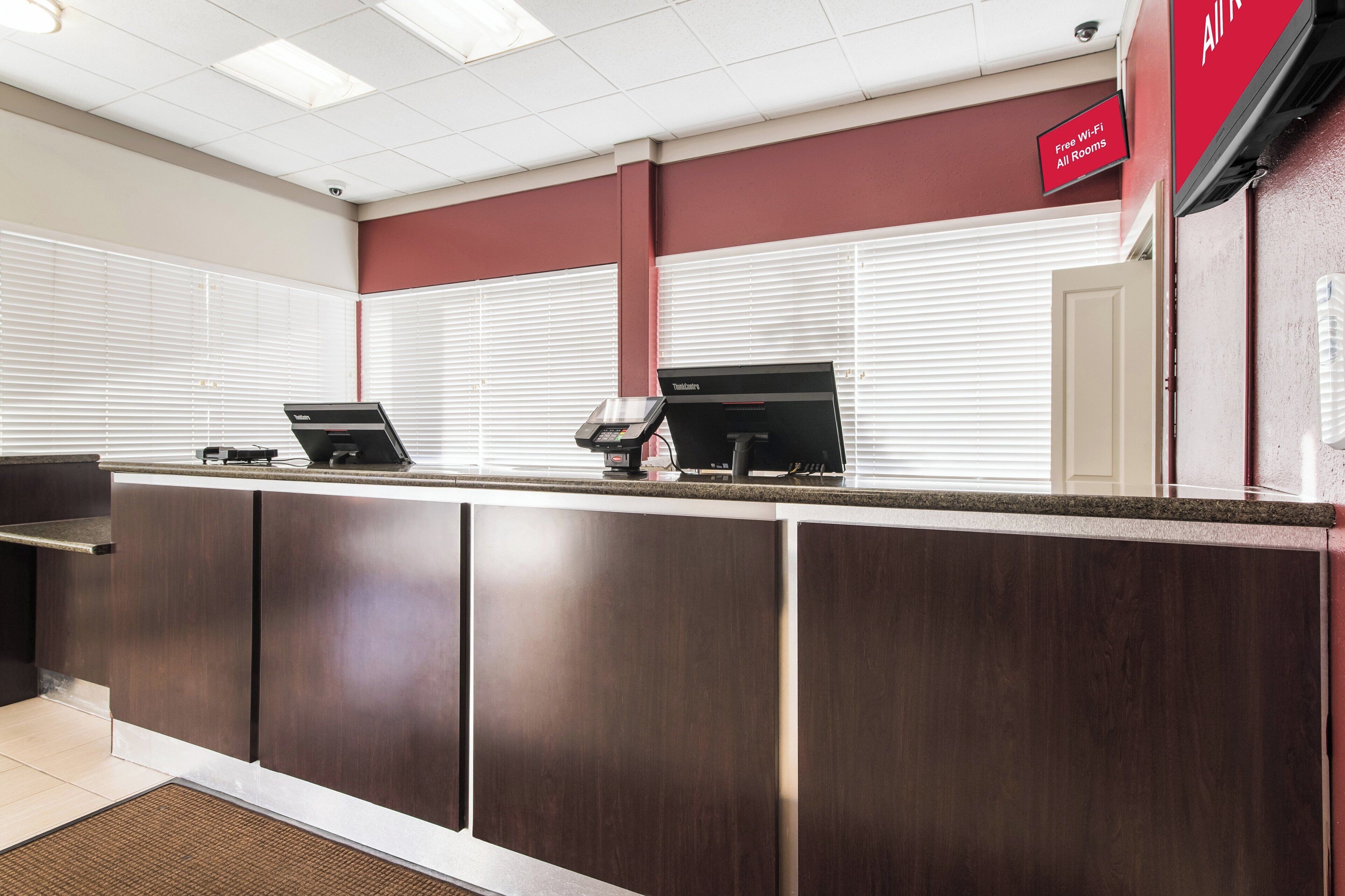 A reception desk with a digital kiosk, a security camera, and a sign indicating free Wi-Fi in all rooms.