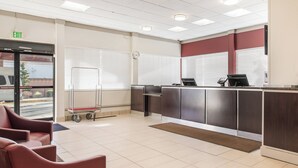 A reception area with a desk, chairs, a clock, and an exit sign. - Red Roof Inn Seattle Airport - SEATAC (SeaTac)