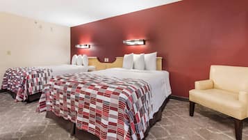 A hotel room with two beds, a sofa, and a red accent wall.