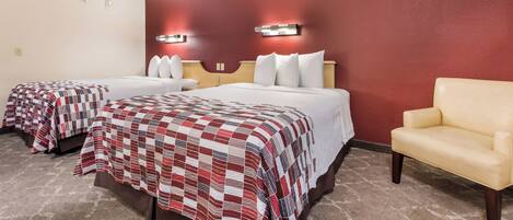 Habitación de hotel con dos camas, un sofá y una pared decorada en rojo.