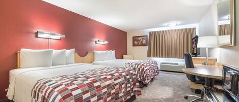 A hotel room with two beds, a desk, a chair, a microwave, and a large mirror.