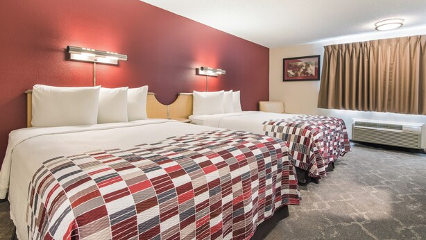 A hotel room with two beds, a red accent wall, and a window with curtains. - Red Roof Inn Seattle Airport - SEATAC (SeaTac)