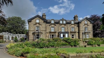Stately hotel with a traditional facade, surrounded by beautifully maintained gardens.