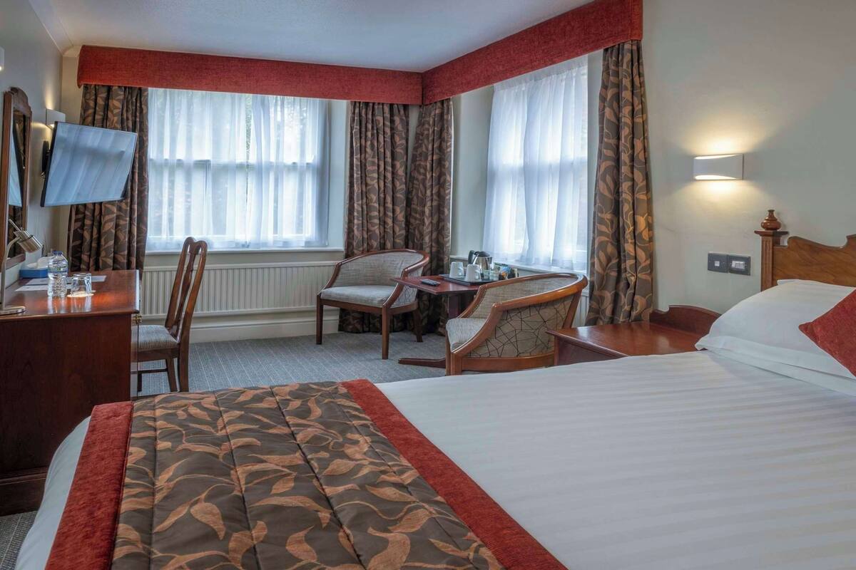 Une chambre d’hôtel équipée d’un lit, d’un bureau, d’une chaise et d’un téléviseur.
