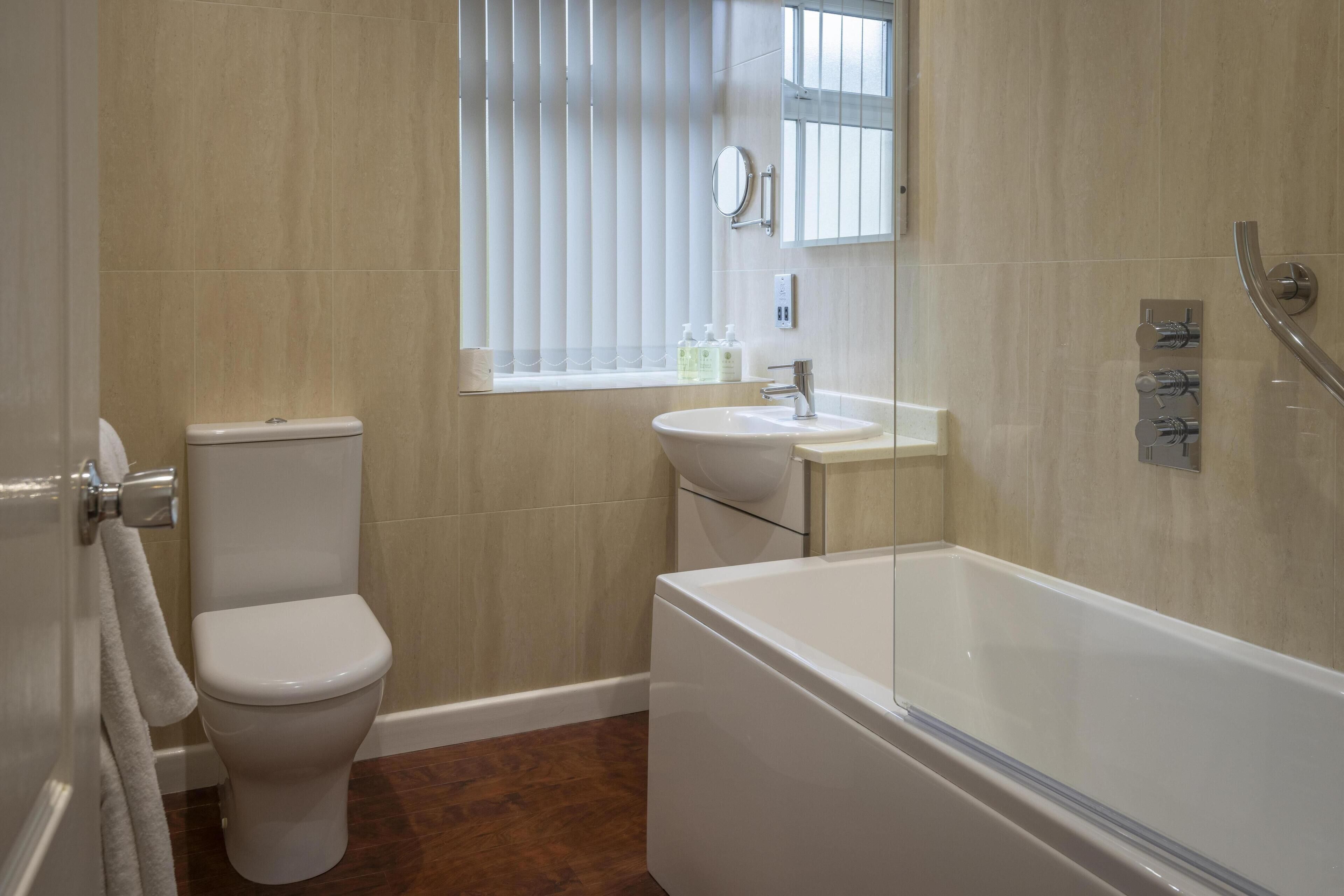 A modern bathroom with a toilet, sink, and bathtub.
