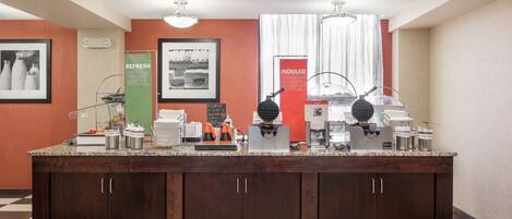 A breakfast bar with coffee machines, a waffle maker, and a sign that reads "REFRESH MEEL SLOPE SLICE."