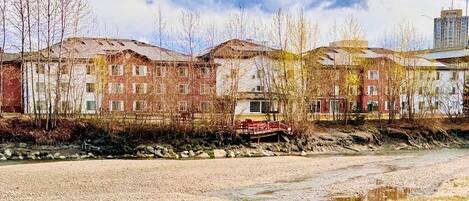 A row of multi-story buildings with a river in the foreground.