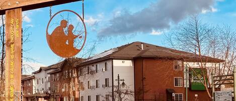 A building with a large garage door, a brick facade, and a sign with a silhouette of a person playing a guitar.