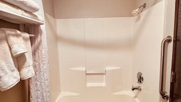 A walk-in shower with a glass door, a towel rack with folded towels, and a wooden floor.