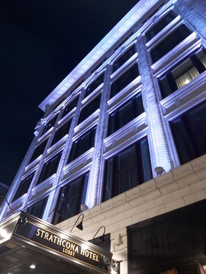 The exterior of the Strathcona Hotel with illuminated windows and a signboard.