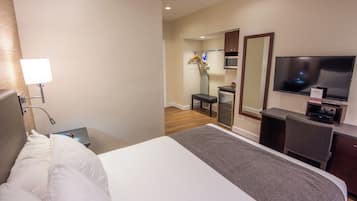 A hotel room with a bed, a desk, a chair, a TV, and a mirror.