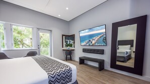 A modern hotel room with a large bed, a TV, a mirror, and a cityscape view. - The Kent Hotel (Miami Beach)