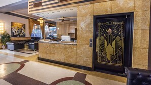 A hotel lobby with a reception desk, seating area, and a decorative door. - The Kent Hotel (Miami Beach)