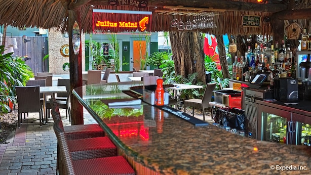 A tiki bar with a neon sign, outdoor seating, and a bar counter. - The Kent Hotel (Miami Beach)