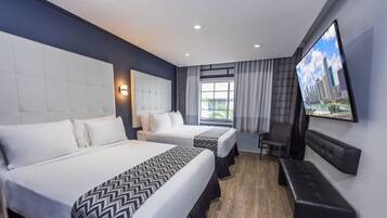 Habitación de hotel con dos camas, un televisor, un banco y vista a la ciudad.