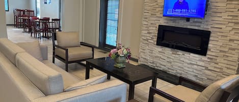 A modern living room with a sofa, armchairs, a coffee table, and a TV mounted on a textured wall.
