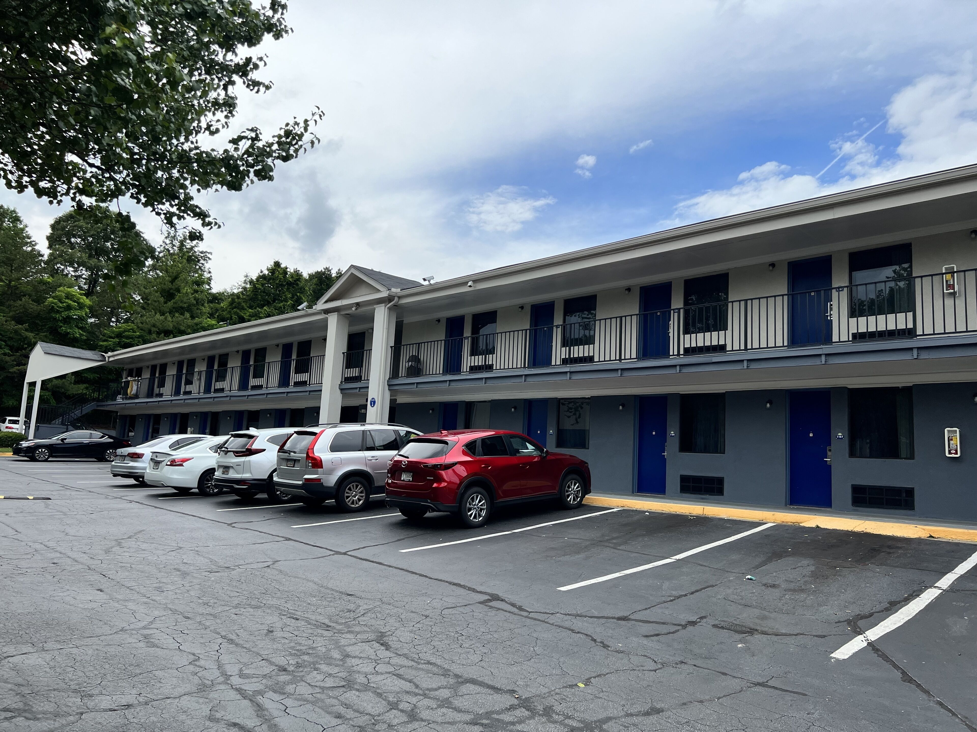 A motel with a parking lot, multiple cars parked, and a building with balconies.