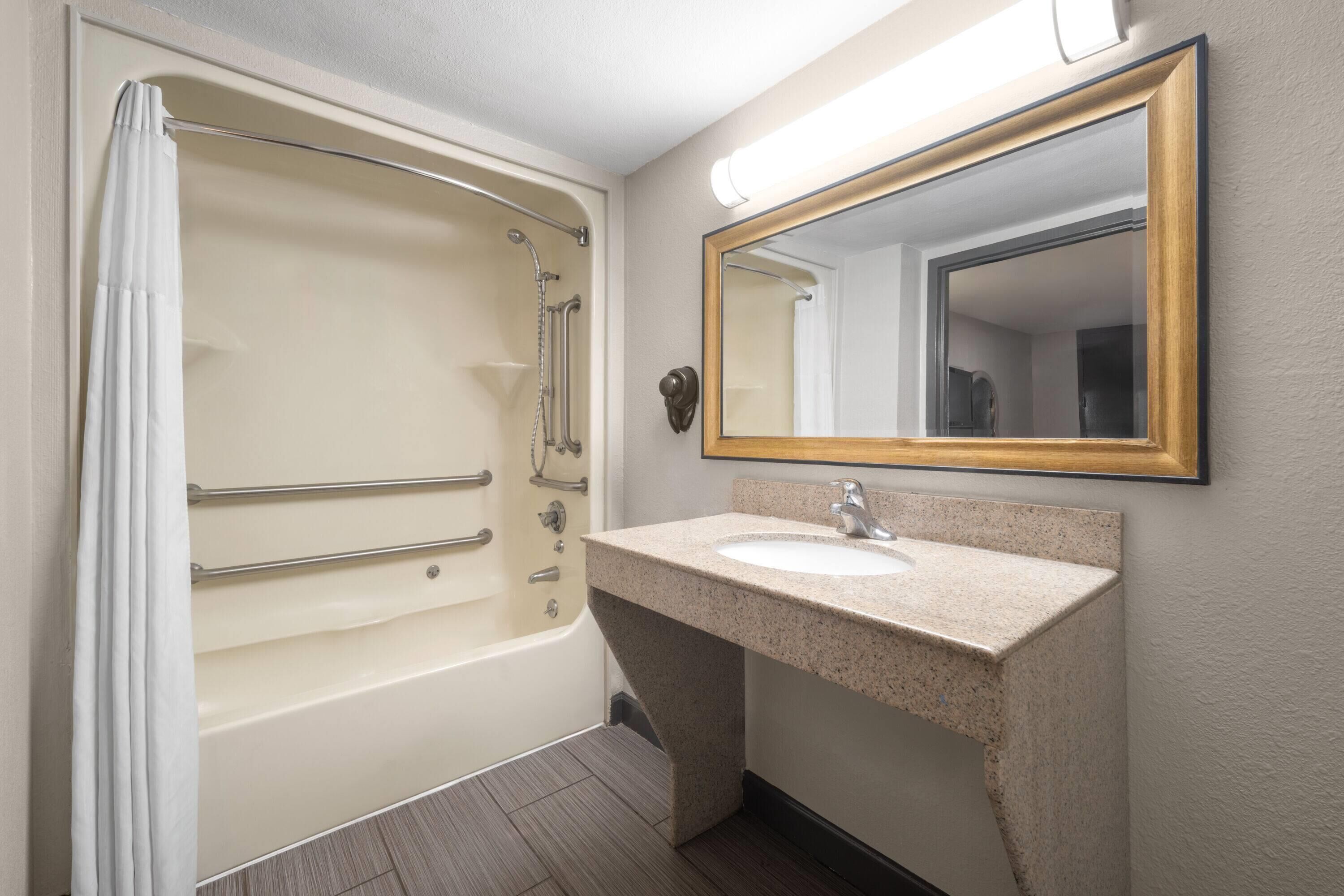 A bathroom with a bathtub, a sink, and a mirror.